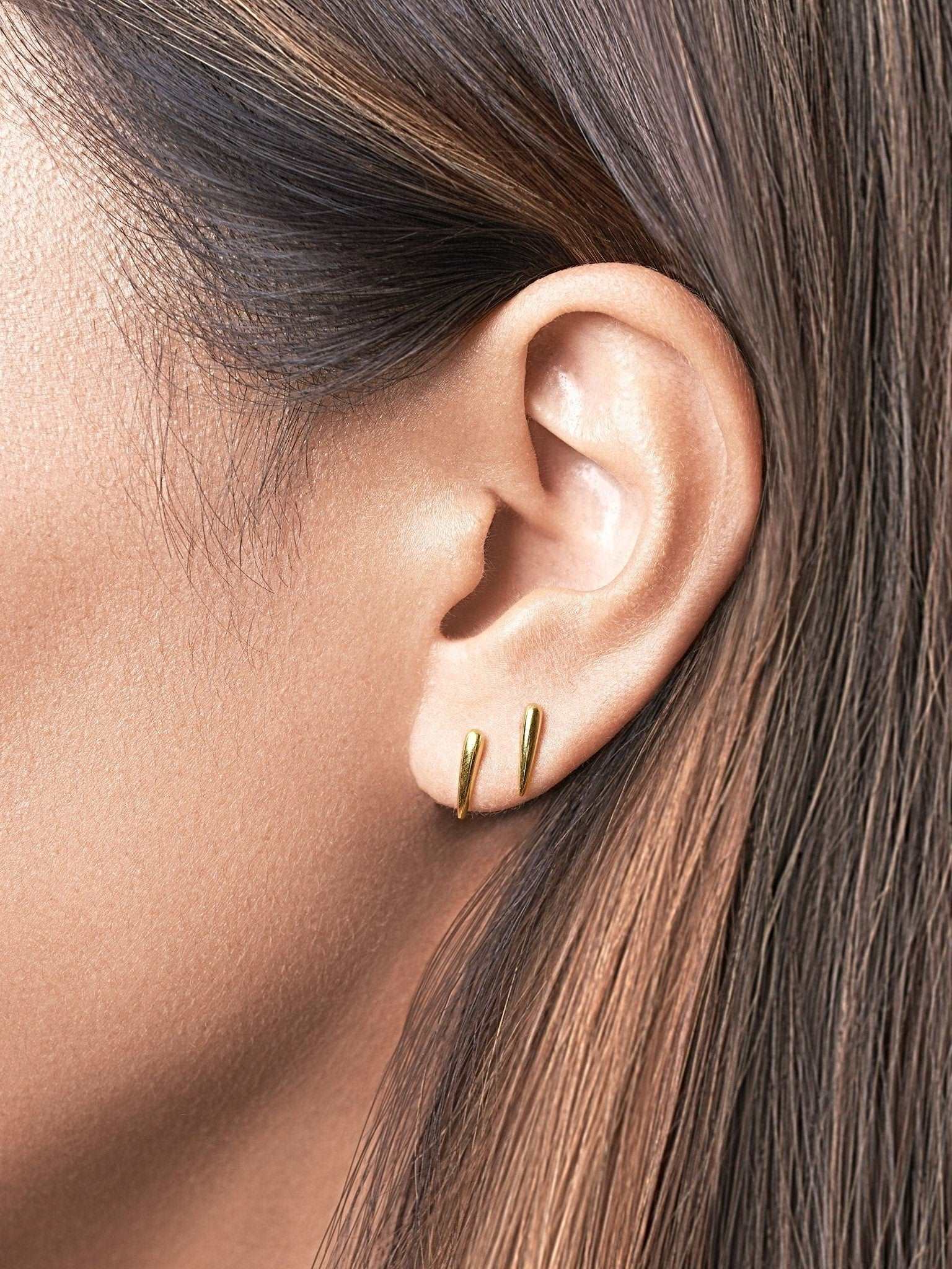 . "Model showcasing Aura Dainty Tusk Earrings in gold with natural light"