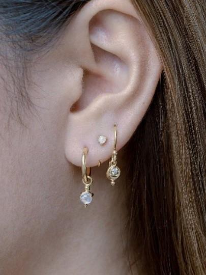 Back view of model wearing gold hoop earrings with dangling moonstone
