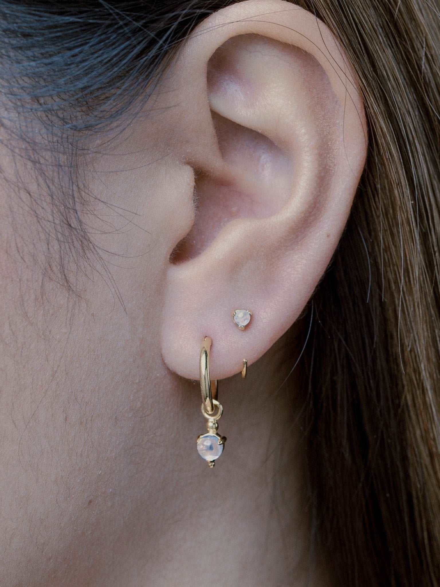 Back side view of model wearing gold hoop earrings with moonstone