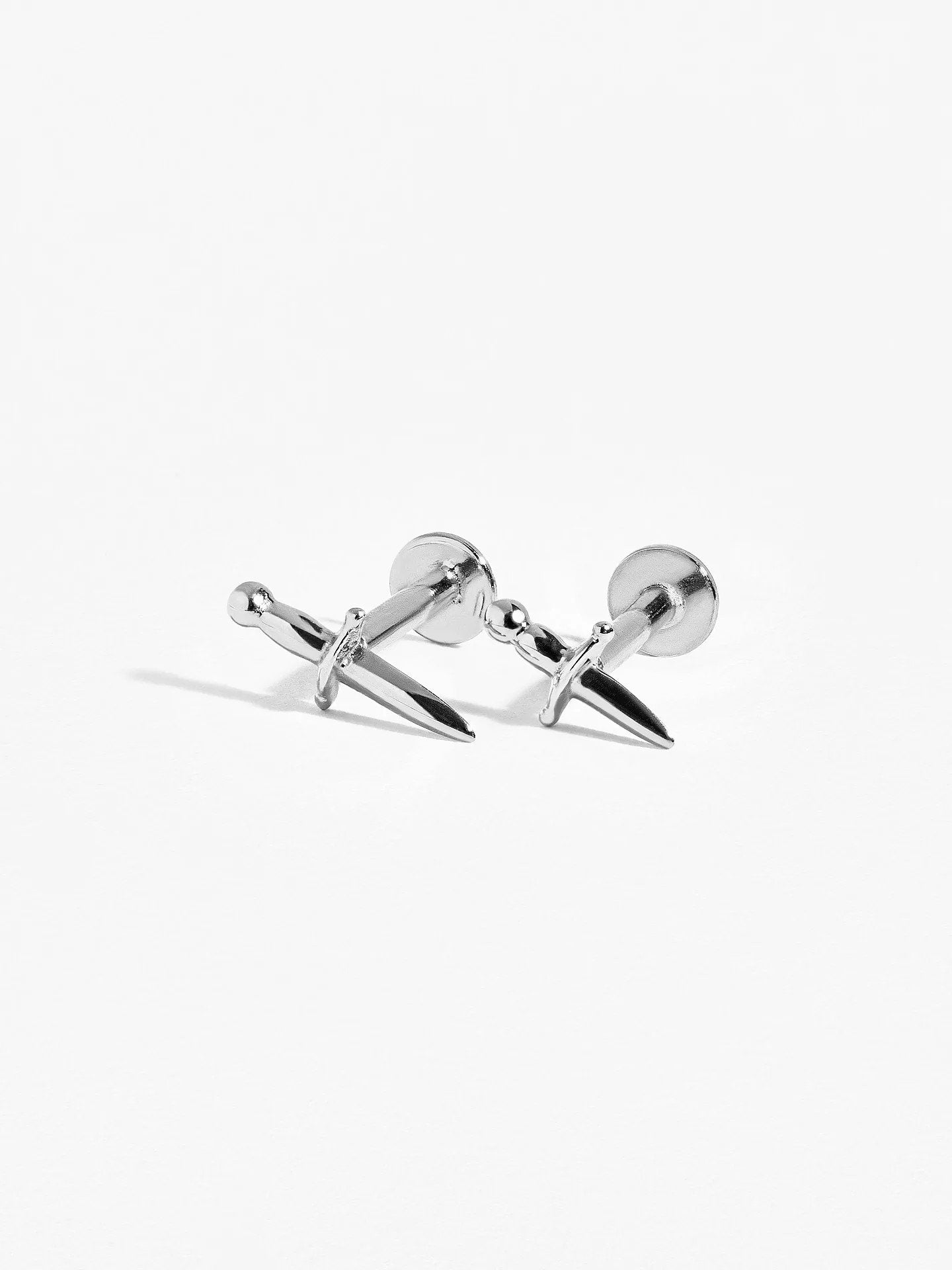 Two Helix Dagger cartilage earrings in sterling silver laying crossed, showing delicate dagger design.
