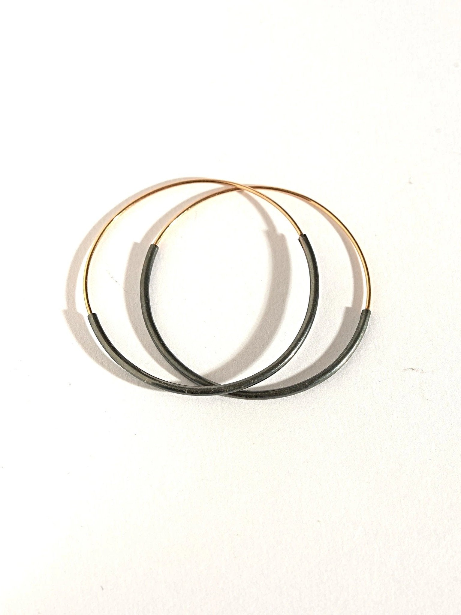 Stacked Kim hoop earrings in gold filled and oxidized silver — layered contrast in clean composition.
