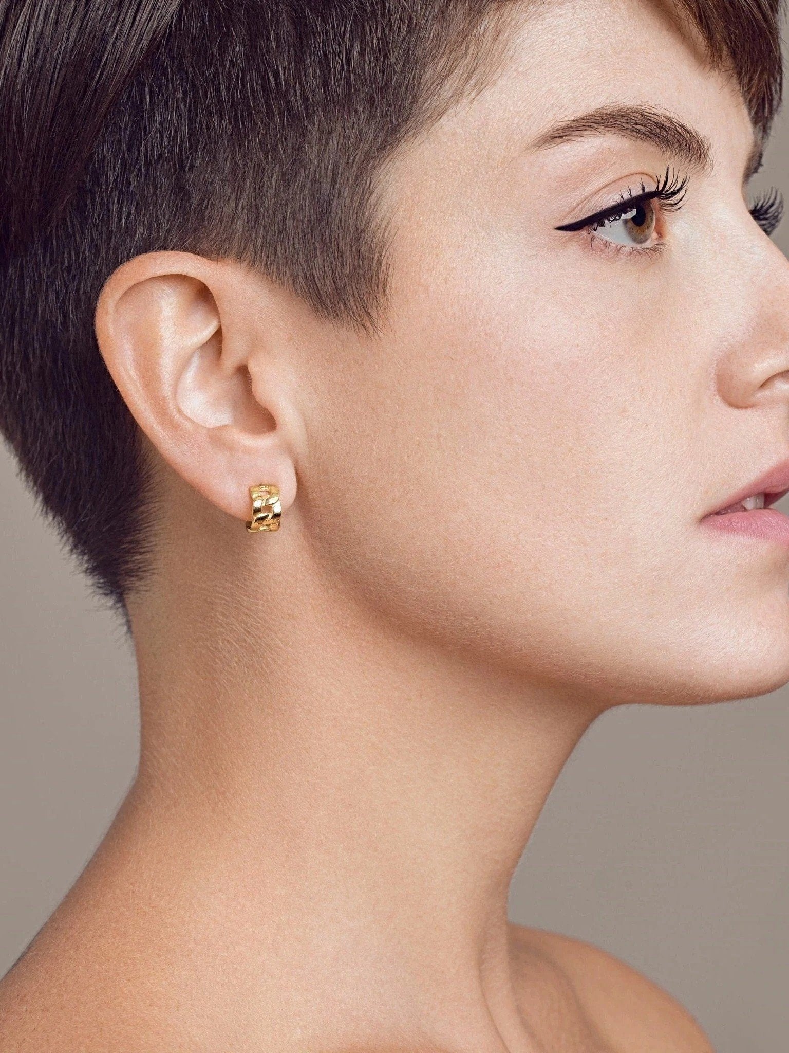  Side profile of short-haired model wearing Meel Gold Hoop Earrings — bold 24K gold-plated hoops with chain link texture.