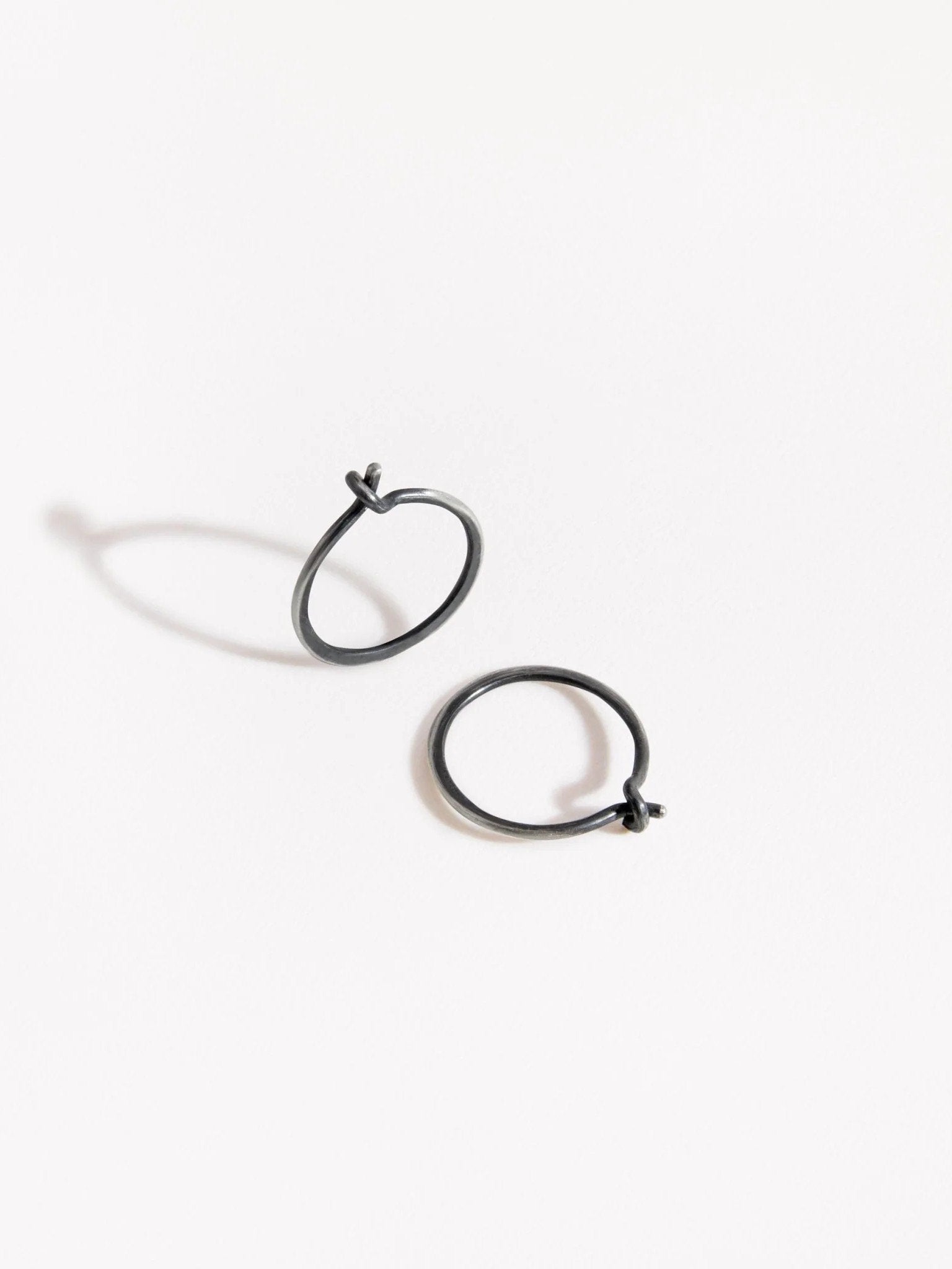  Black and silver hoop earrings with a minimalist aesthetic on a white background.
