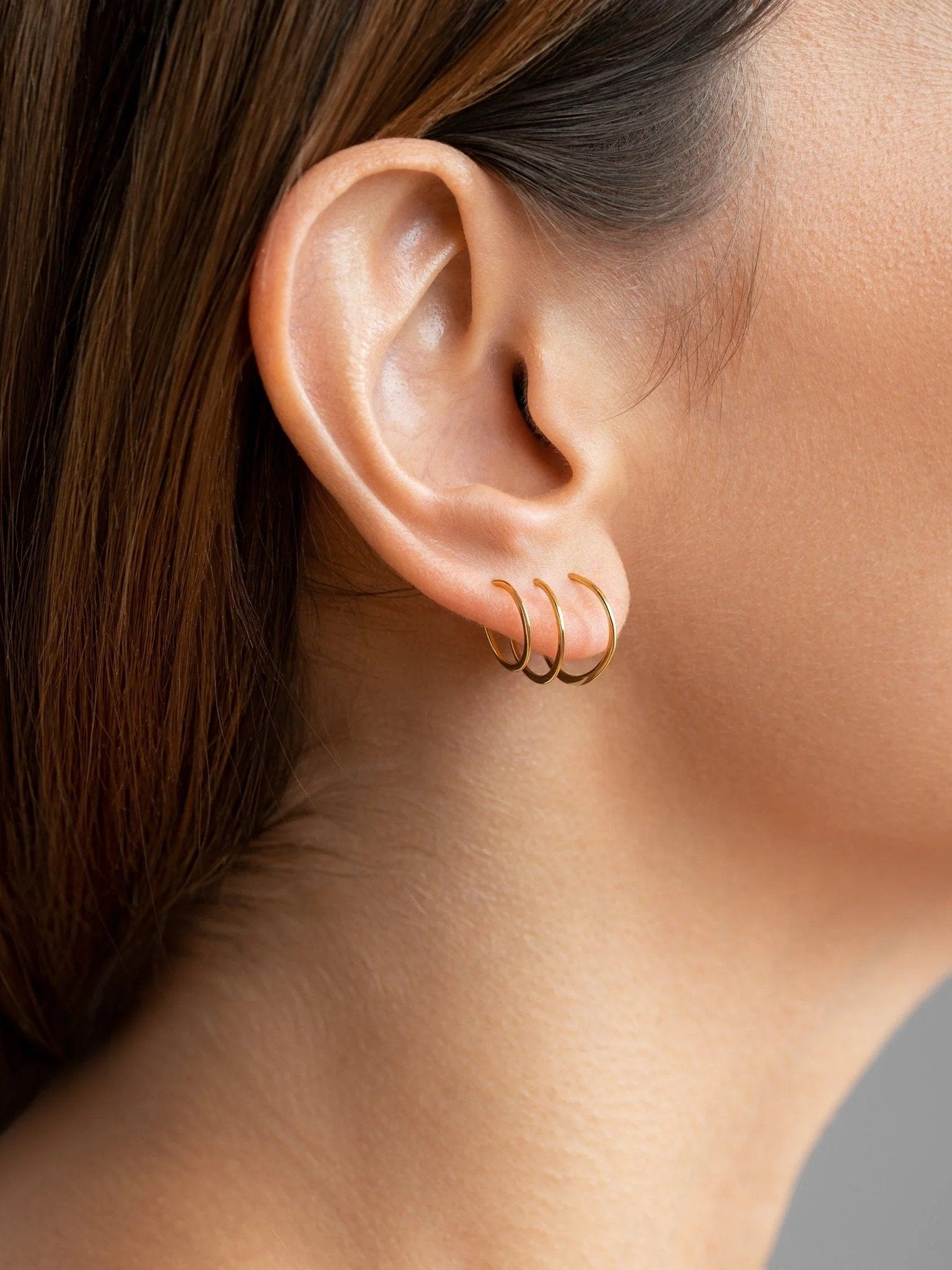 Close-up of a model wearing yellow gold hoop earrings, elegant style.
