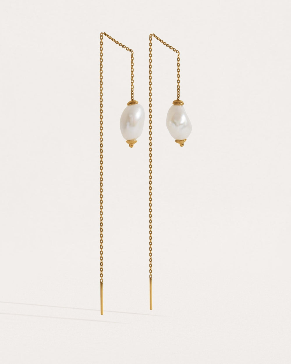 Two pairs of threader earrings in silver and gold finishes — freshwater pearl drops on fine chain.