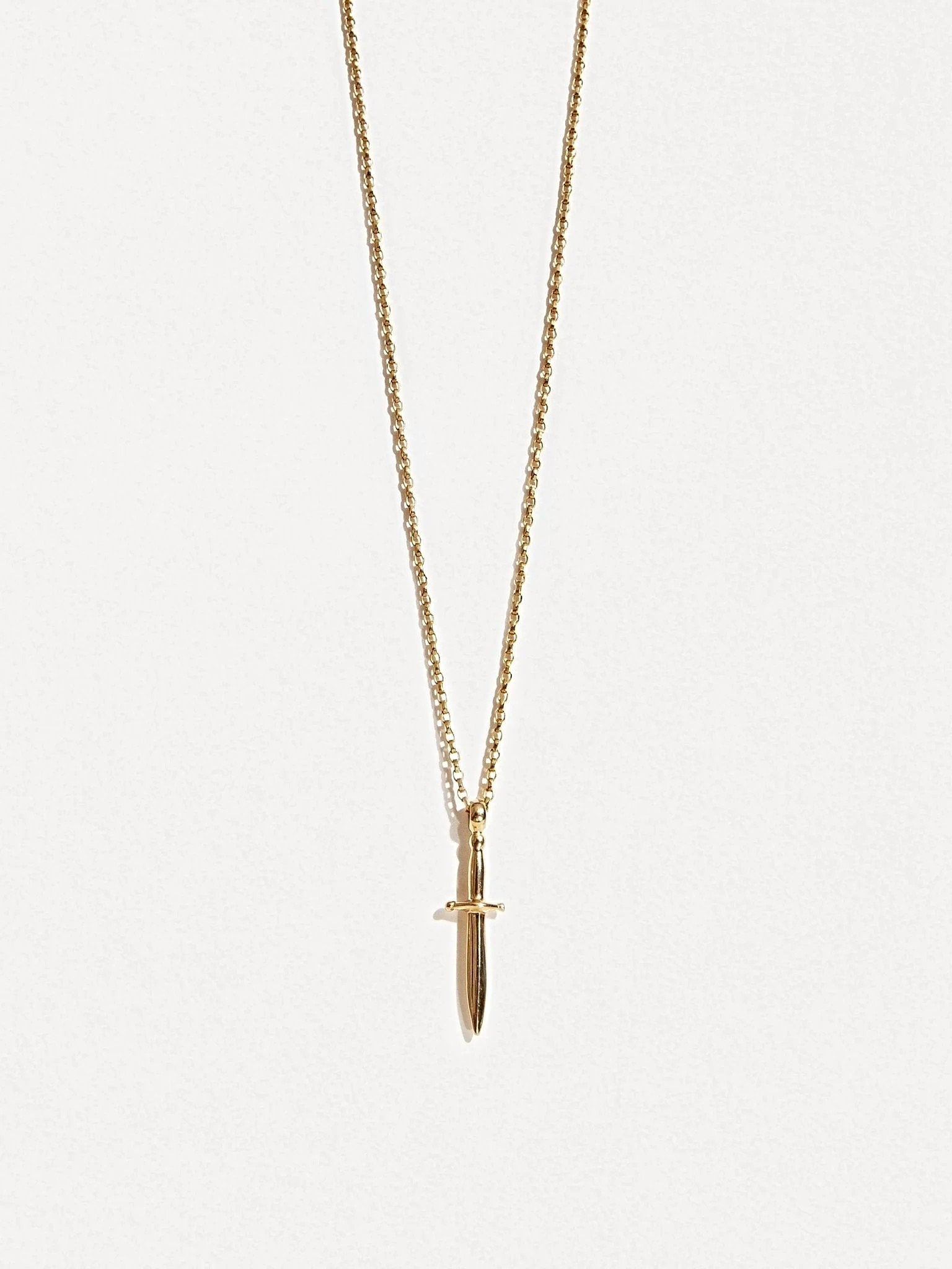 Gold dagger necklace on white background, front-facing product shot.