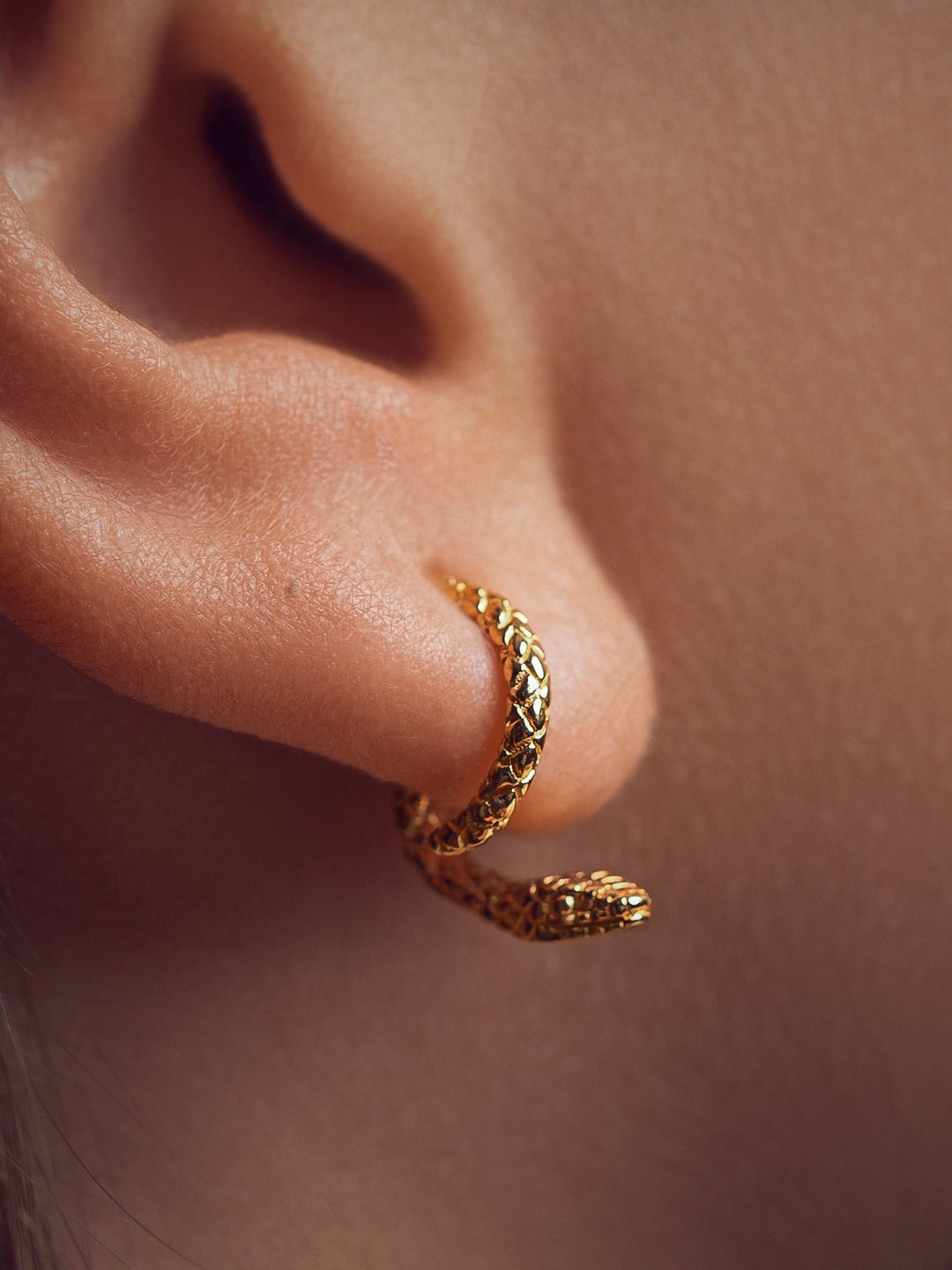  Close-up of the 24K gold plated snake ear jacket, highlighting its sleek curves and refined texture.