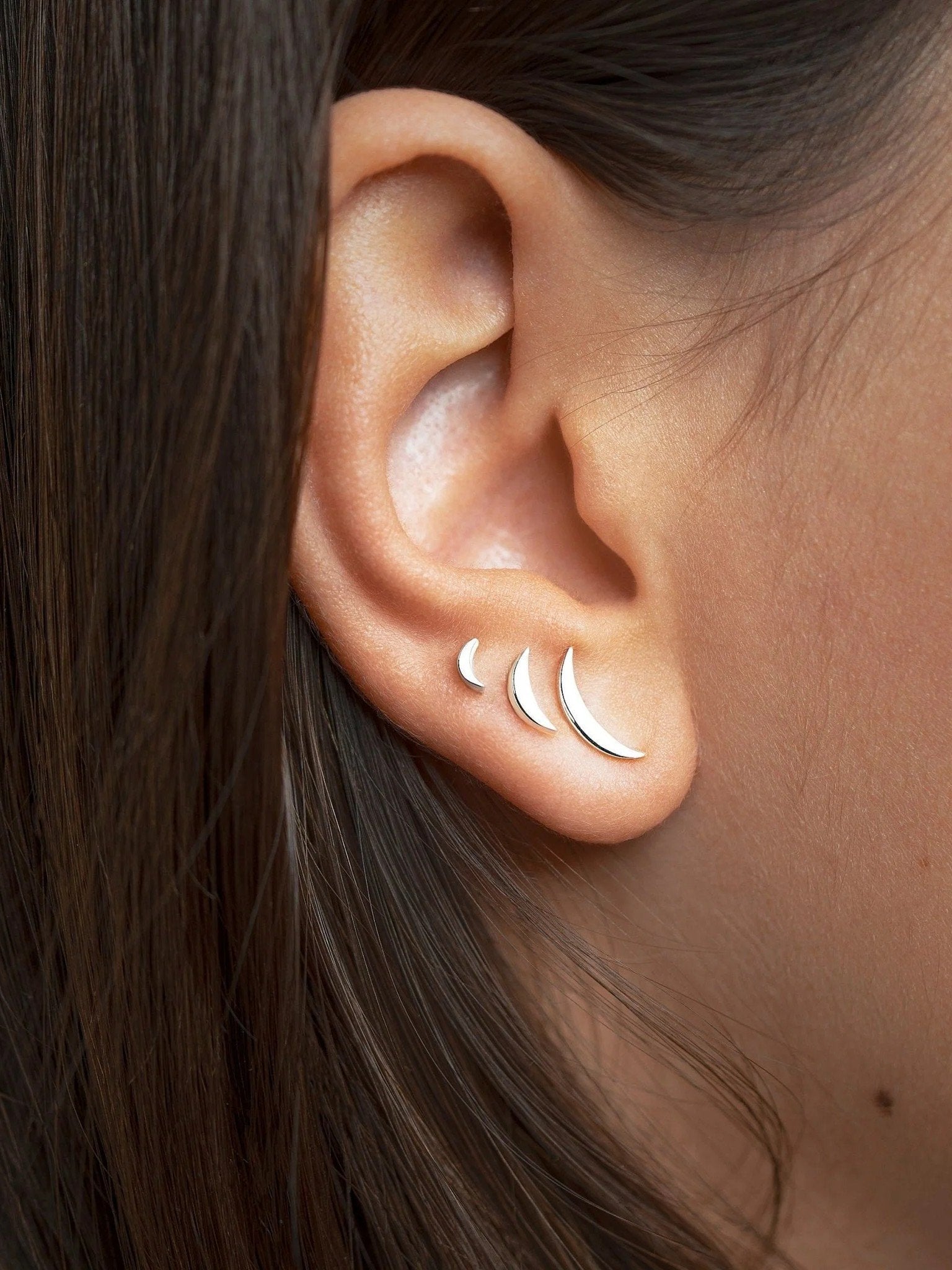 Three silver stud earrings with secure backs, side view