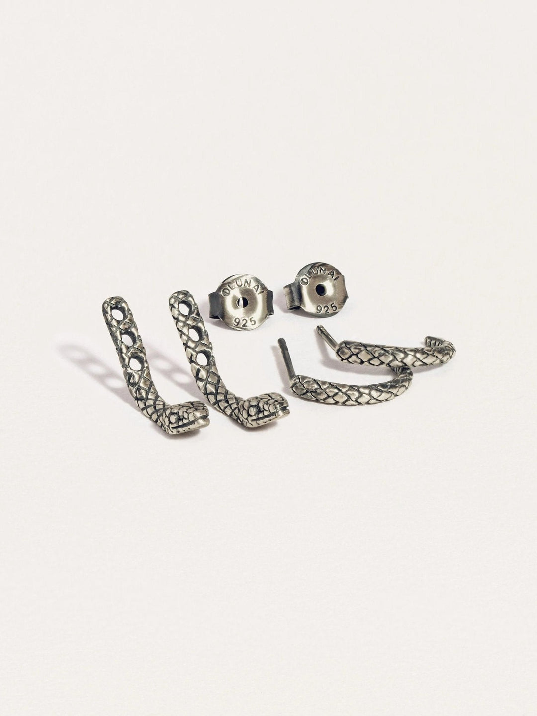 Pair of snake ear jackets in sterling silver oxide photographed on white background.