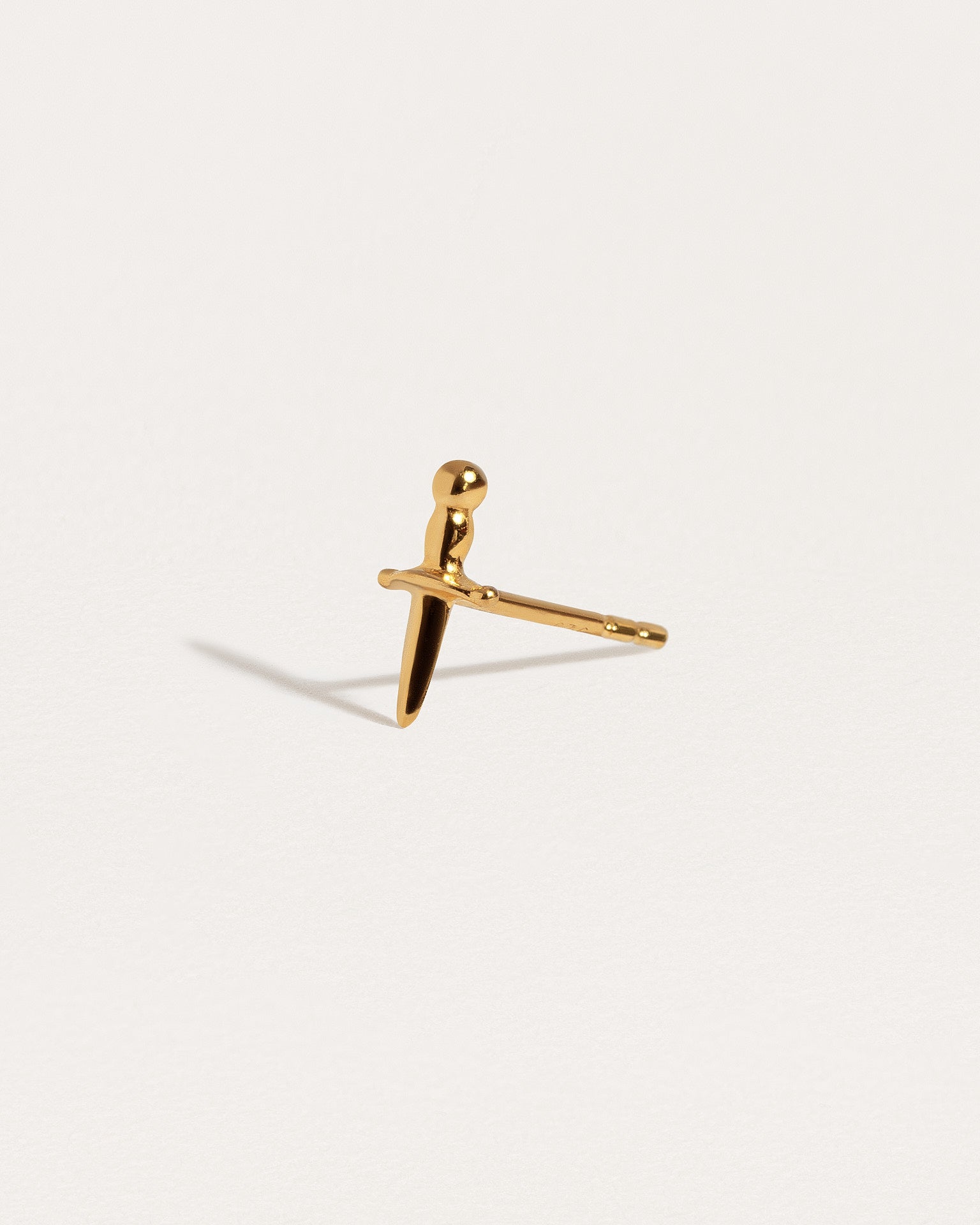 Gold-plated Tessa Sword Stud Earrings held in hand for size reference"