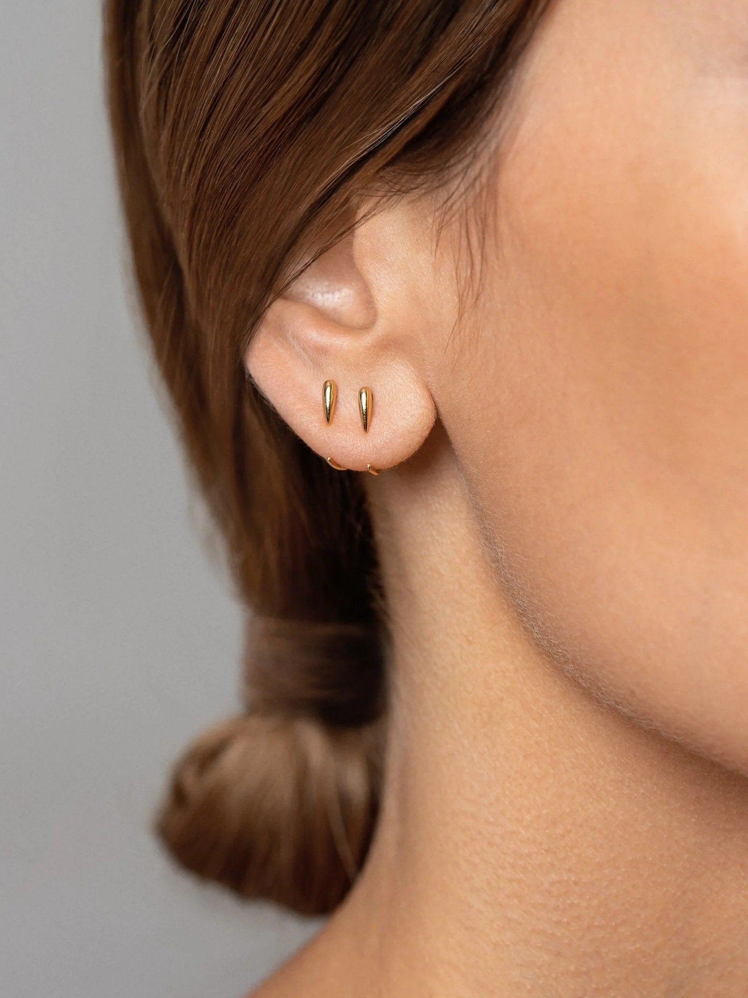 Luppa gold earring worn — polished finish and hugging shape styled close to ear.