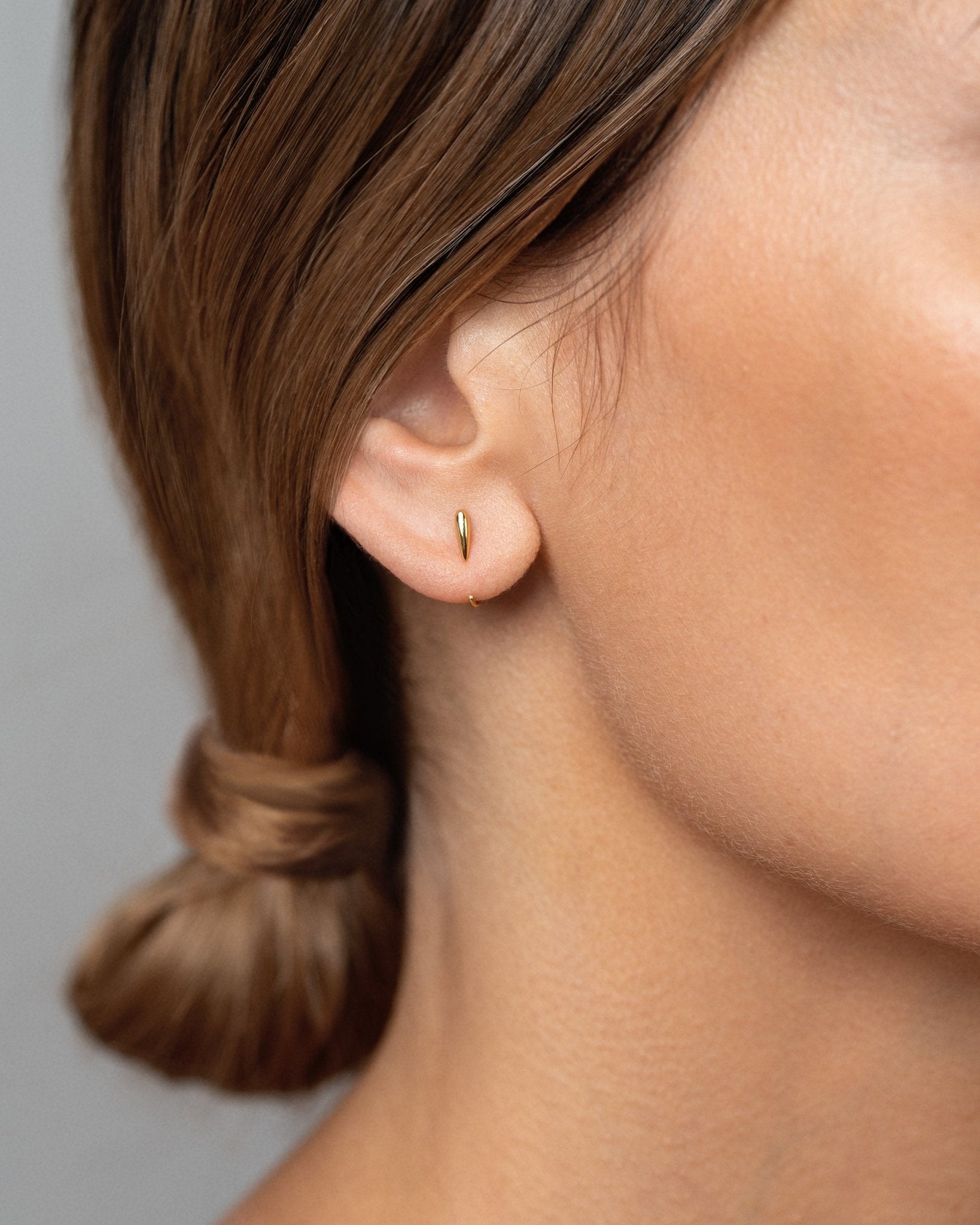 Luppa gold hug hoop earring worn — modern, minimal styling with soft glow.